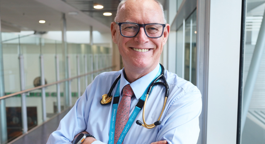 an experienced doctor in a hospital corridor with a gold stethoscope around his neck