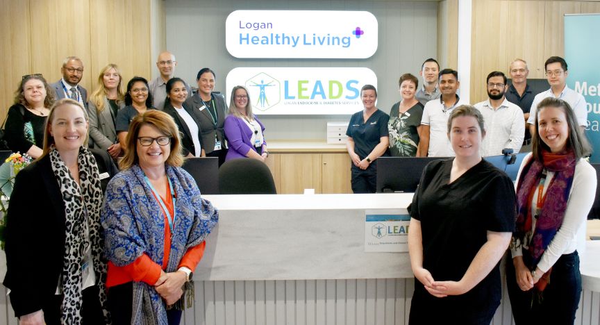 A group of people standing in front of a reception desk at Logan Healthy Living and LEADS, a diabetes support center.