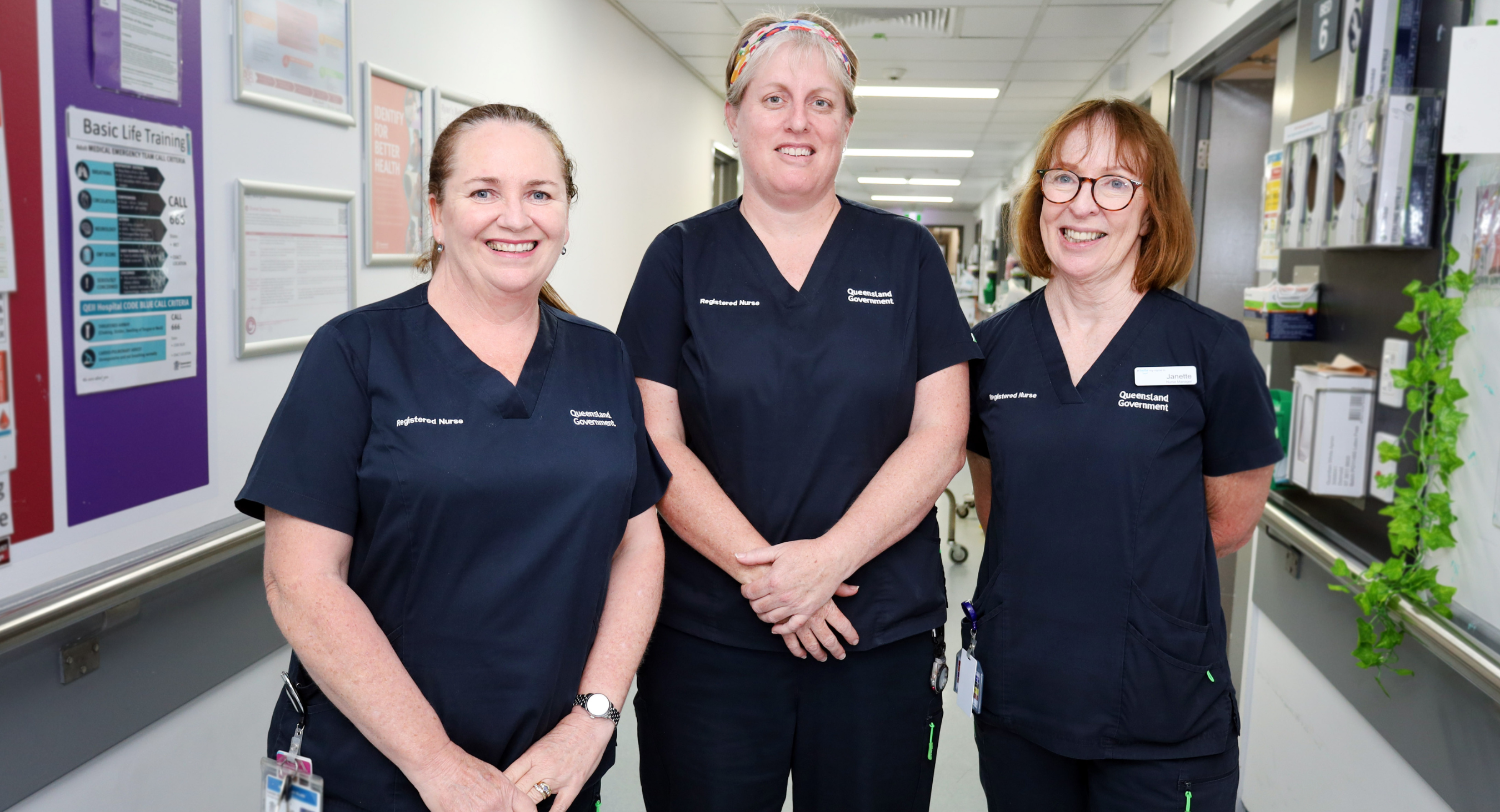 Three female nurses standing in hallway smiling at QEII Hospital.