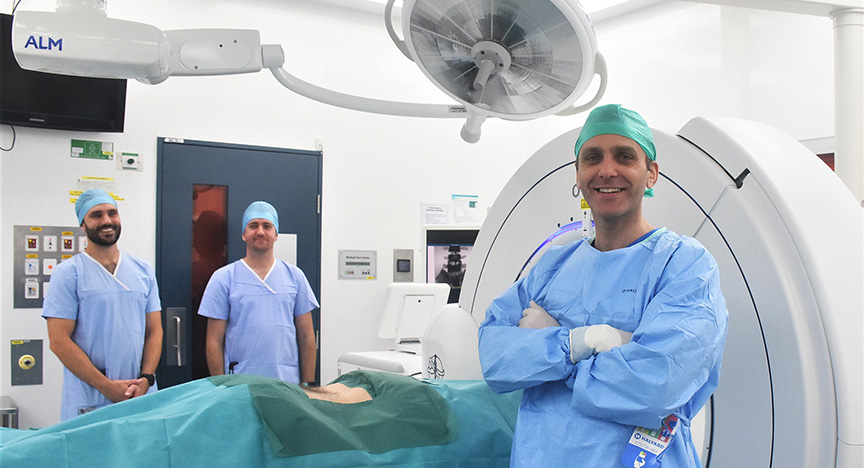 Medical staff in a surgical room with a patient on a table, preparing for a procedure using a CT machine.