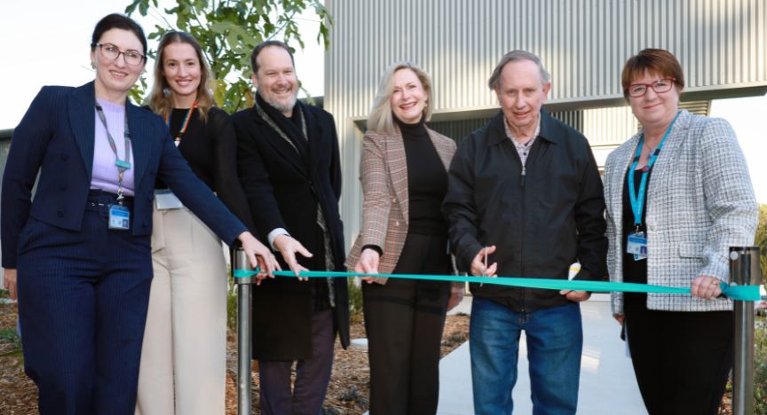 A group of people cutting a ribbon at the opening of a new Allied Health and Ambulatory Care Services building at QEII Hospital.