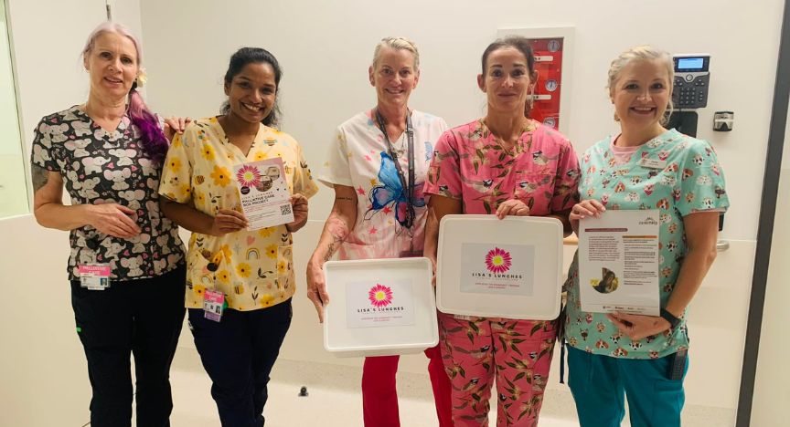 Five healthcare workers in colorful scrubs hold informational materials about a palliative care partnership at Logan Hospital.