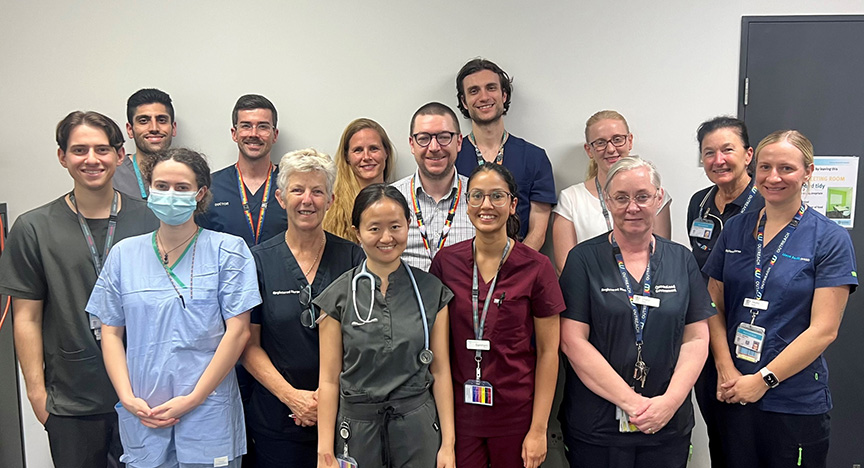 A group of healthcare professionals in scrubs and uniforms standing together in a hospital setting.