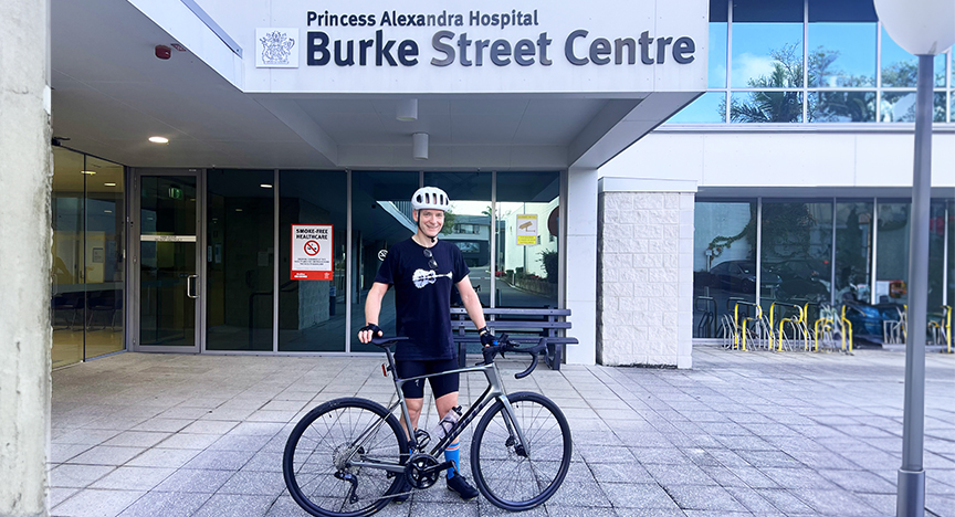 A person with a bicycle stands in front of the Princess Alexandra Hospital Burke Street Centre entrance.