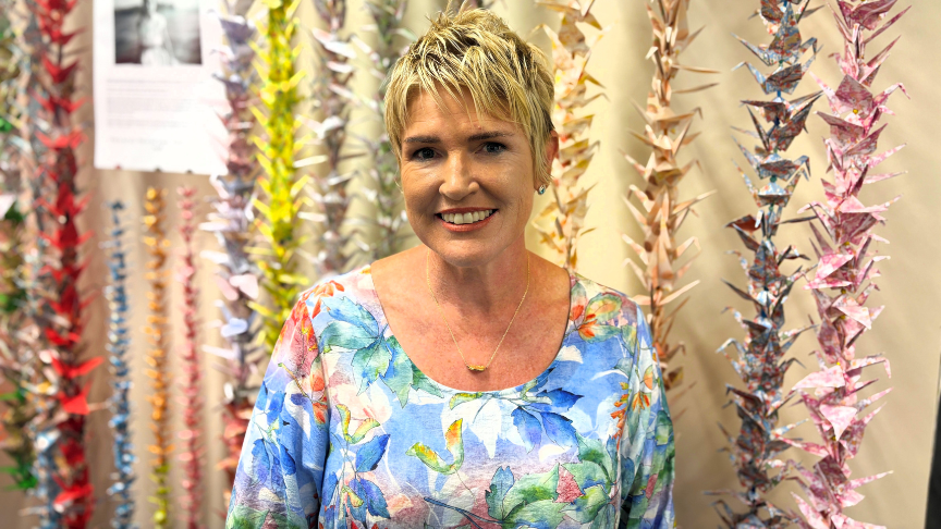 Jeanette stands in front of a wall of paper cranes