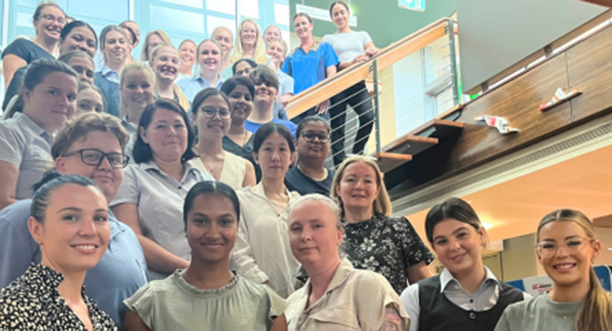 A group of new nurse graduates standing on a staircase inside a building, posing for a photo.