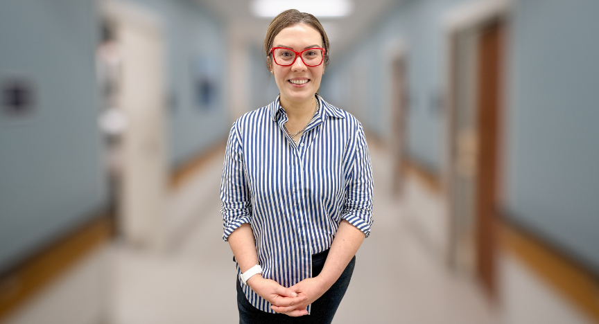 A person wearing a striped shirt stands in a hallway with blue walls and wooden accents.