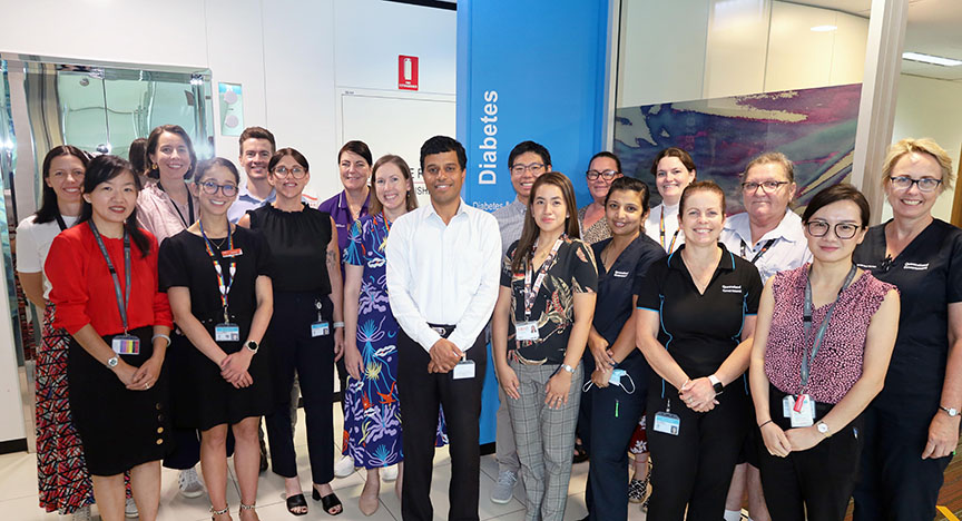 A group of healthcare professionals stands together in front of a sign that reads Diabetes in a medical facility.