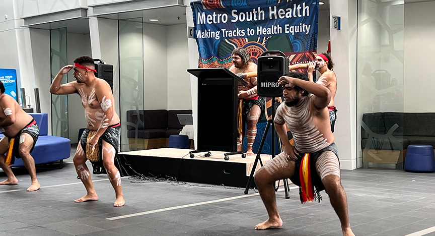 First Nations dancers perform in traditional attire at a Metro South Health event promoting health equity.