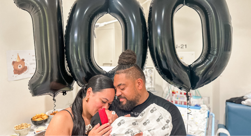 Taki family in front of number 100 balloons 