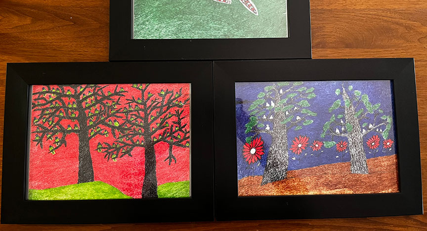 Three framed artworks depict stylized trees and flowers in vibrant colors. The left image shows trees with a red background, and the right image shows trees with a blue background.