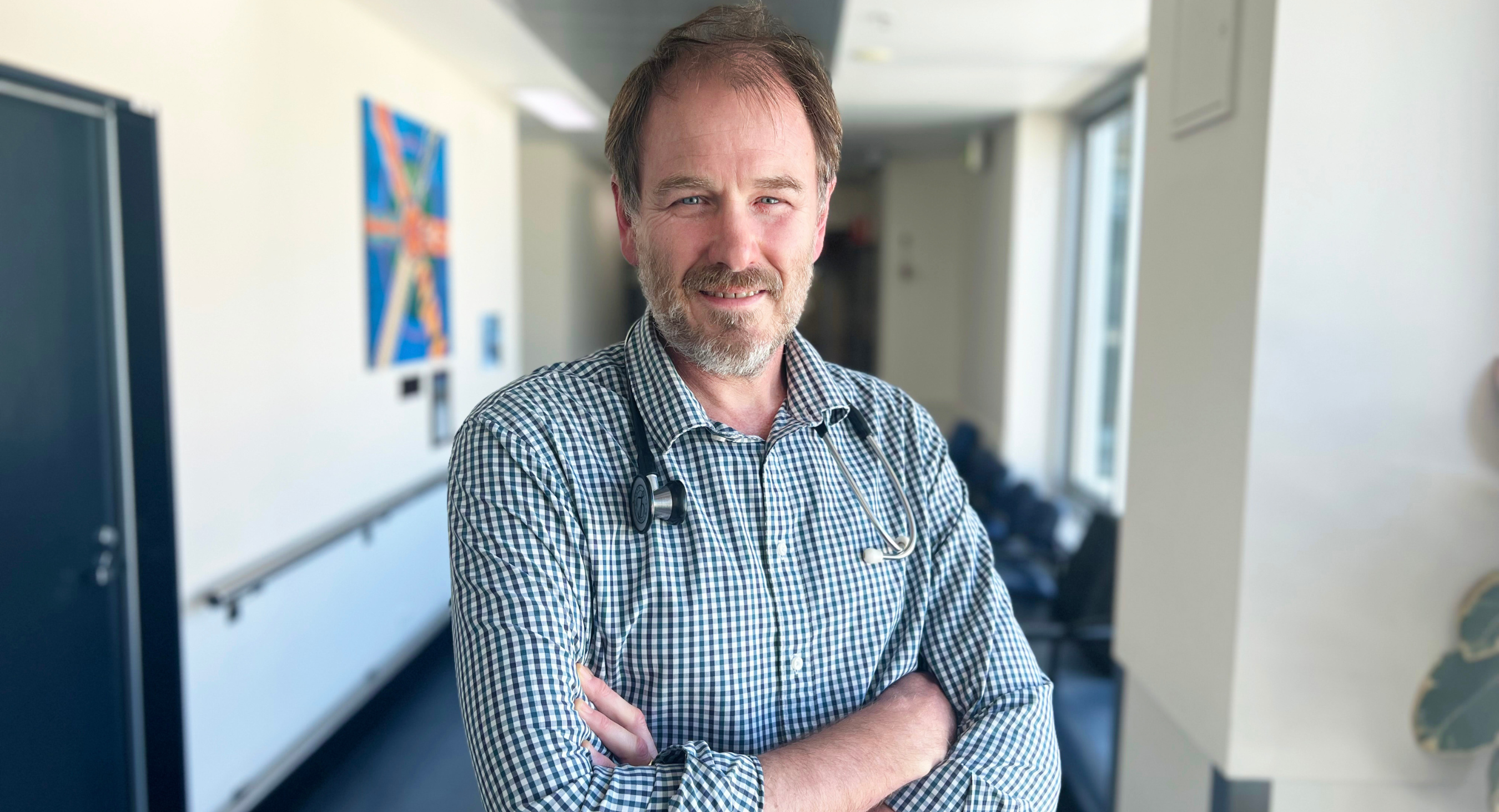 Doctor standing in hallway with arms crossed smiling