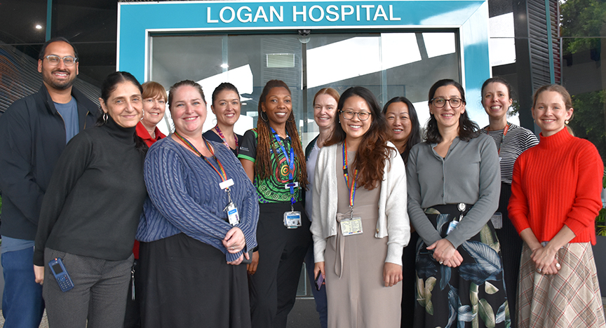 A group of people standing in front of Logan Hospital, wearing ID badges and lanyards, posing for a photo.