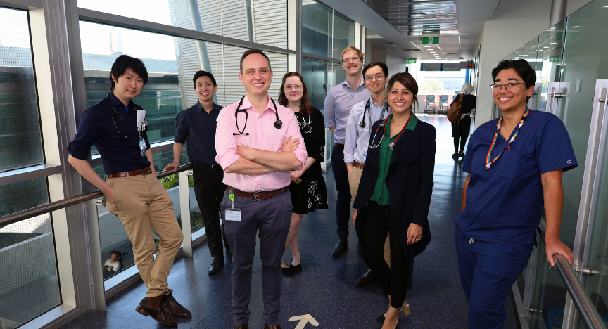 A group of doctors standing in a hospital corridor, some wearing stethoscopes and medical attire.